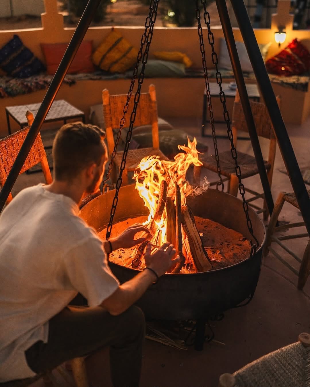 Fire & Drums Night Traveller warming up by a campfire in a desert camp at night – Merzouga