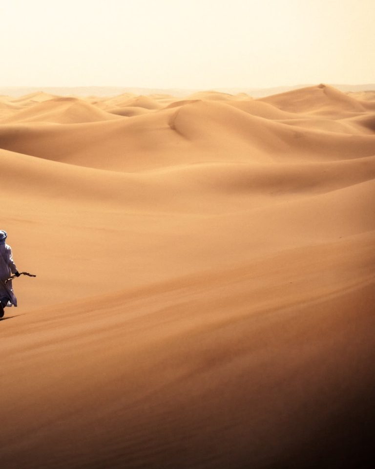 Guided Walking Tour Person walking among wide desert dunes in Merzouga – Merzouga
