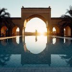 Moroccan arch reflected in a hotel pool at sunset – Merzouga, Morocco