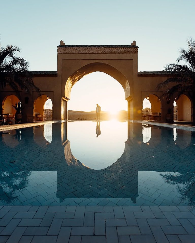 Private Transport in Morocco Moroccan arch reflected in a hotel pool at sunset – Merzouga