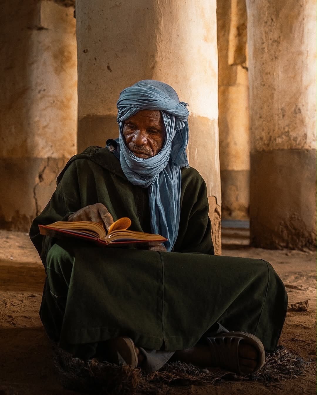 4x4 Desert Excursion Berber man reading in a traditional Moroccan doorway – Merzouga
