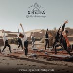 Dihyoga group doing yoga on rugs in the desert – Merzouga, Morocco