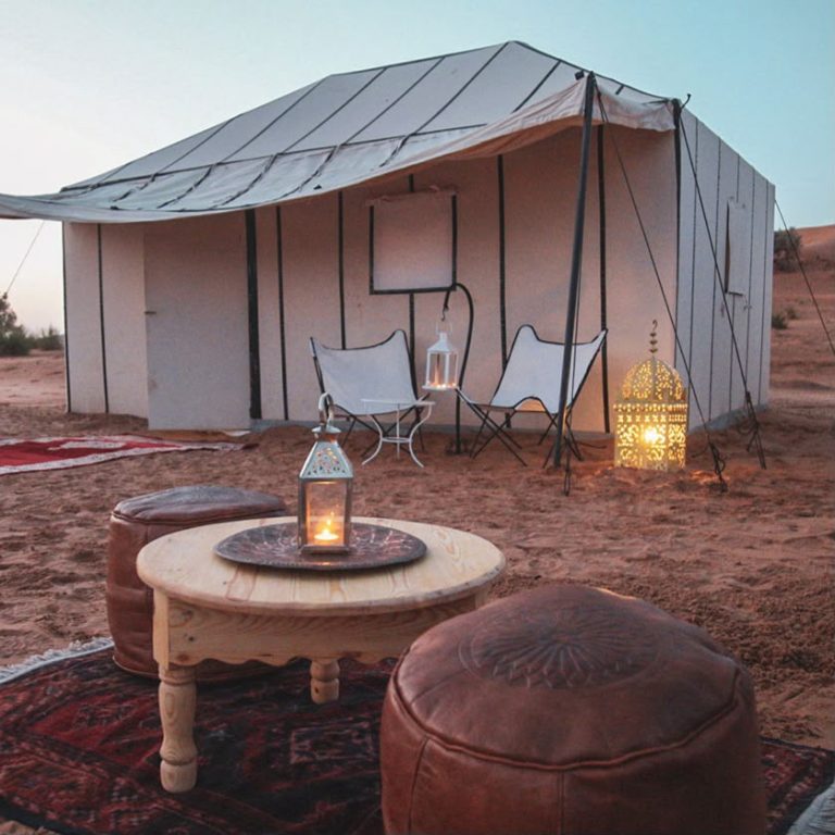 White desert camp tent with a lounge area at dusk – Merzouga