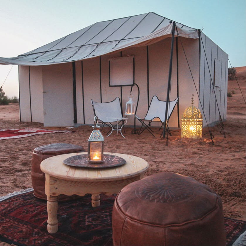 White desert camp tent with a lounge area at dusk – Merzouga