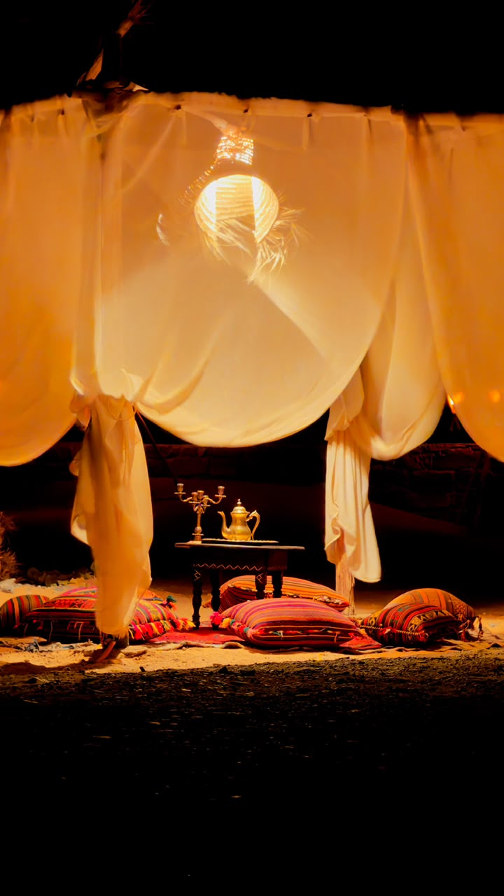 Fire & Drums Night Tent lounge with cushions lit by warm lights at night – Merzouga