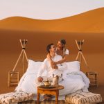 Couple relaxing on a romantic dune bed at sunset – Merzouga, Morocco