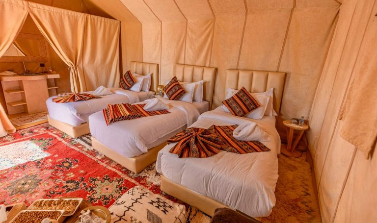 Desert camp suite with beds and colourful blankets – Merzouga
