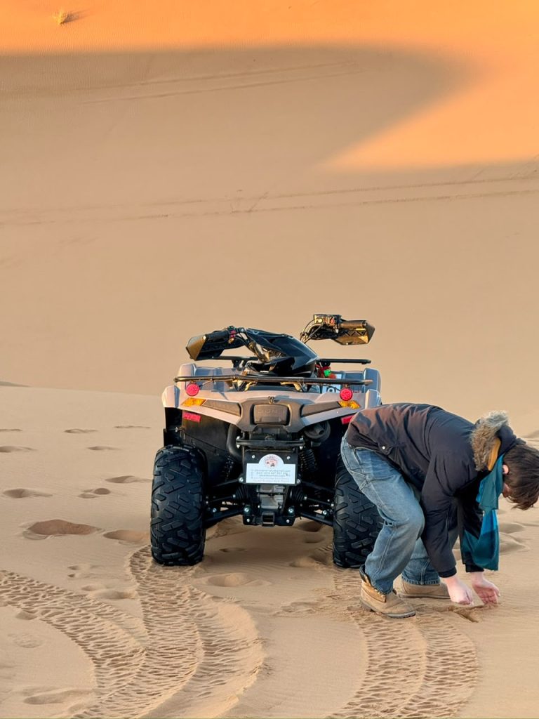 ATV Quad Bike Rider next to an ATV quad bike in the dunes – Merzouga