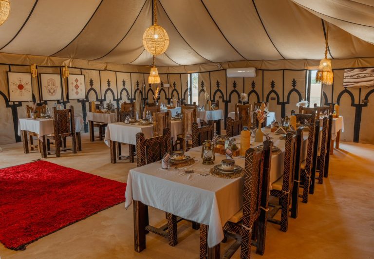 Large restaurant tent of a desert camp with set tables – Merzouga